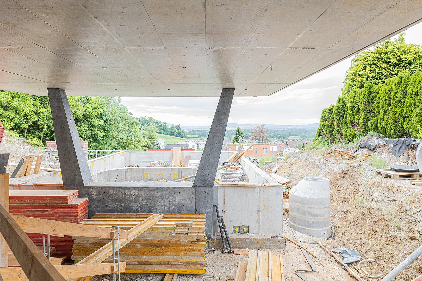 Architecture Photography of an exterior of the construction-site at Winkelhaus by architects Estudio KMMK, construction by atelier rosinus, structure by schnetzer puskas. Pool side with impressive concrete structure.