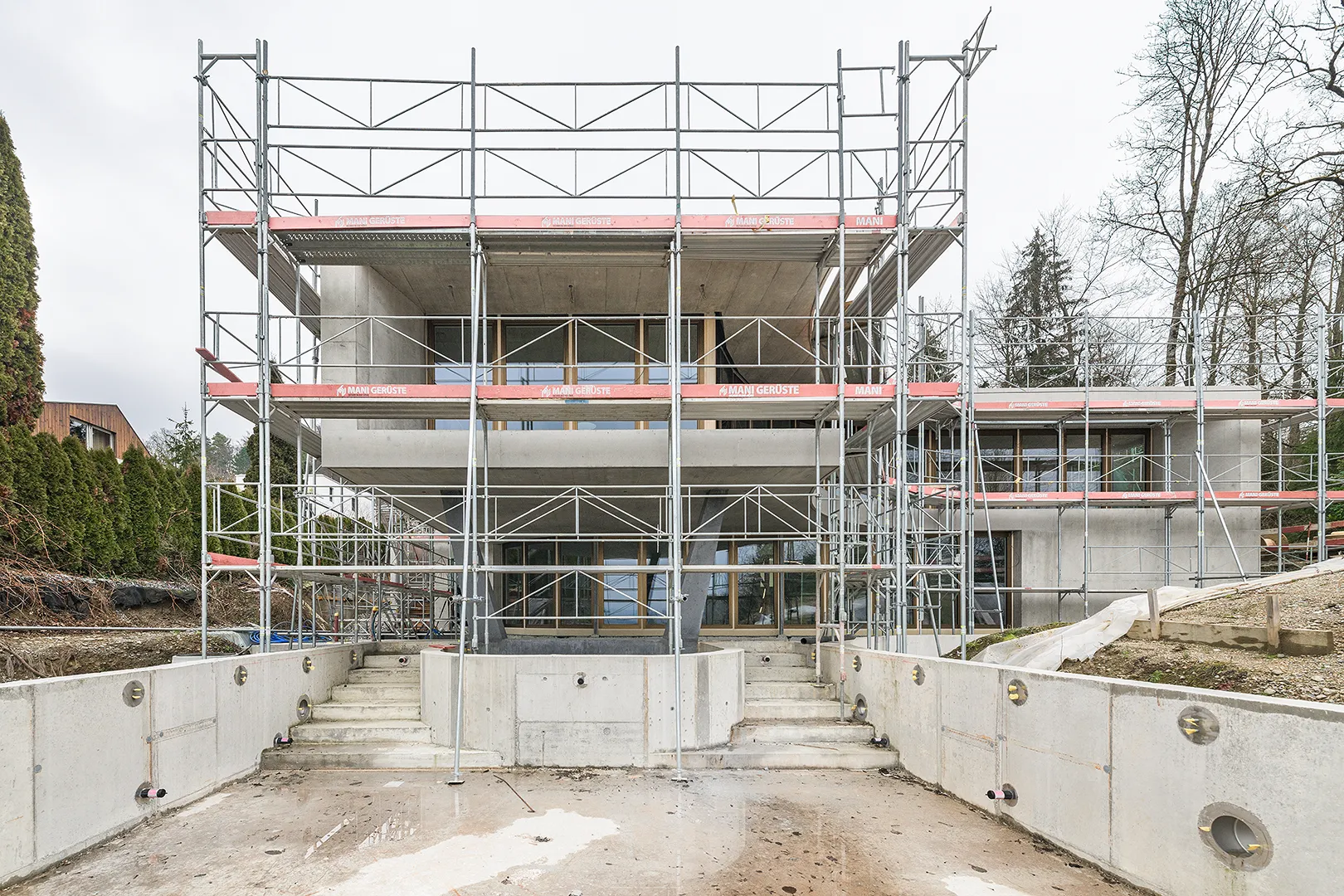 Architecture Photography of an exterior of the construction-site at Winkelhaus by architects Estudio KMMK, construction by atelier rosinus, structure by schnetzer puskas. Pool side with impressive concrete structure.