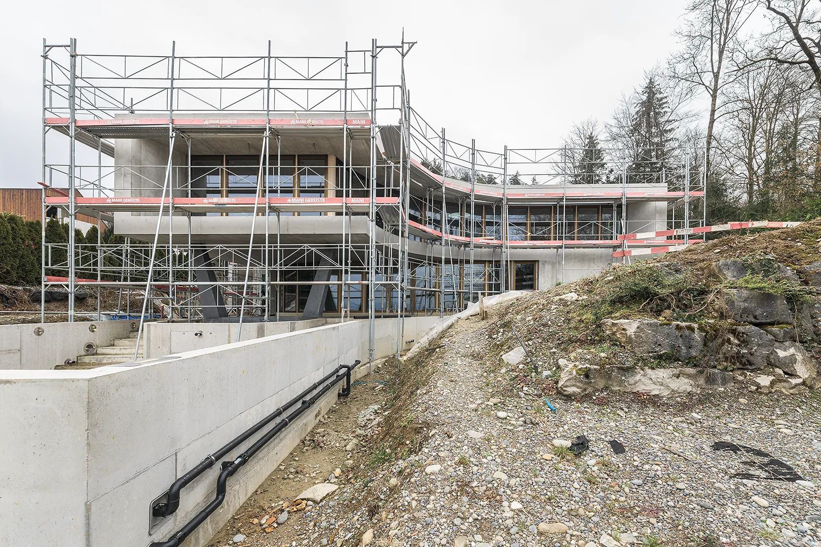 Architecture Photography of an exterior of the construction-site at Winkelhaus by architects Estudio KMMK, construction by atelier rosinus, structure by schnetzer puskas. Pool side with impressive concrete structure.