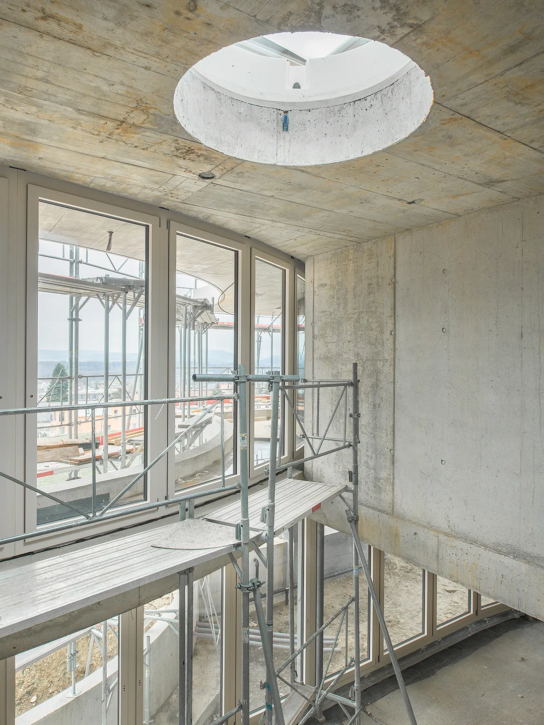 Architecture Photography of an interior of the construction-site at Winkelhaus by architects Estudio KMMK, construction by atelier rosinus, structure by schnetzer puskas. Modular windows and round sky-light on display.