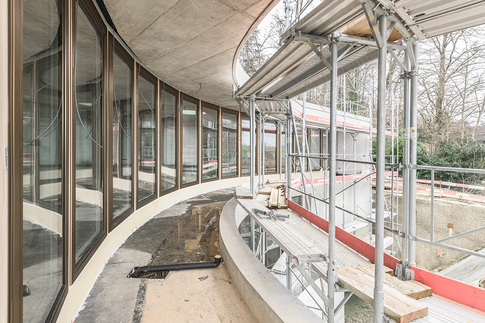 Architecture Photography of an exterior of the construction-site at Winkelhaus by architects Estudio KMMK, construction by atelier rosinus, structure by schnetzer puskas. Modular windows on the view with beautiful reflections.