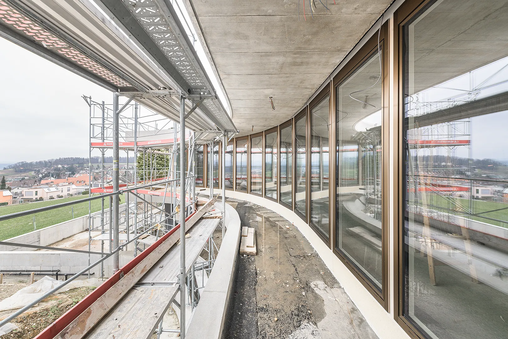 Architecture Photography of an exterior of the construction-site at Winkelhaus by architects Estudio KMMK, construction by atelier rosinus, structure by schnetzer puskas. Modular windows on the view with beautiful reflections.