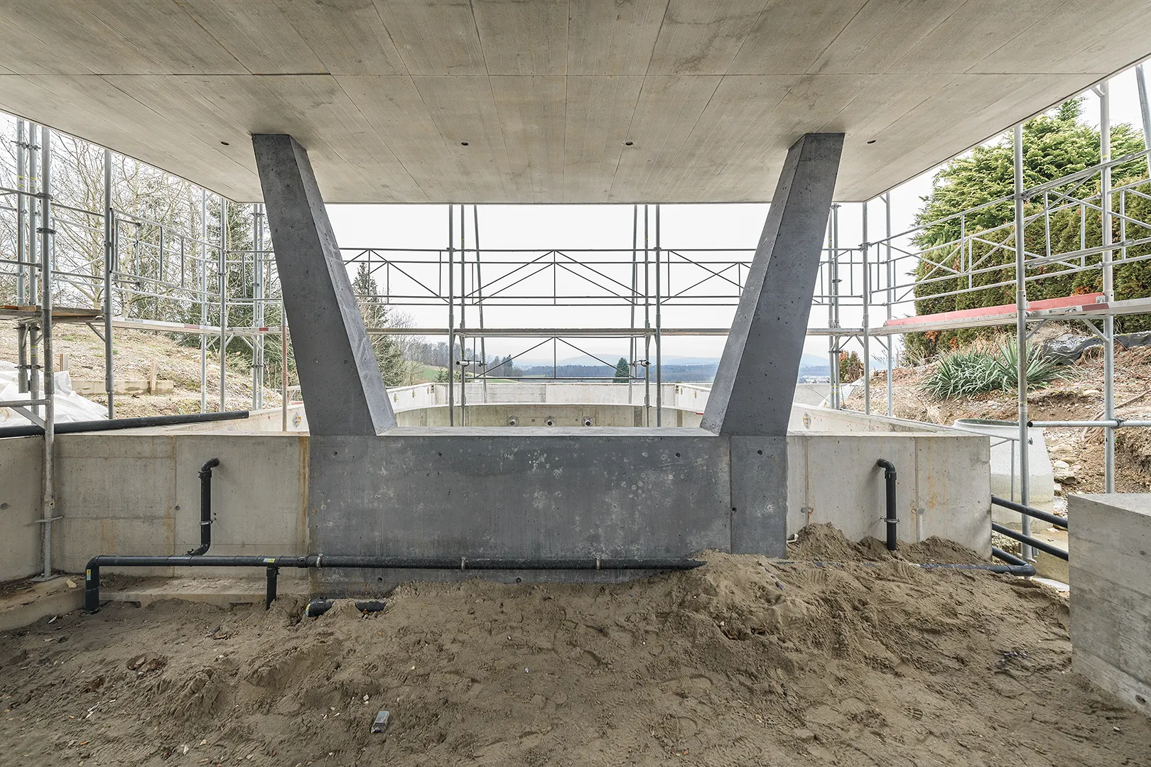 Architecture Photography of an exterior of the construction-site at Winkelhaus by architects Estudio KMMK, construction by atelier rosinus, structure by schnetzer puskas. Pool side with impressive concrete structure.