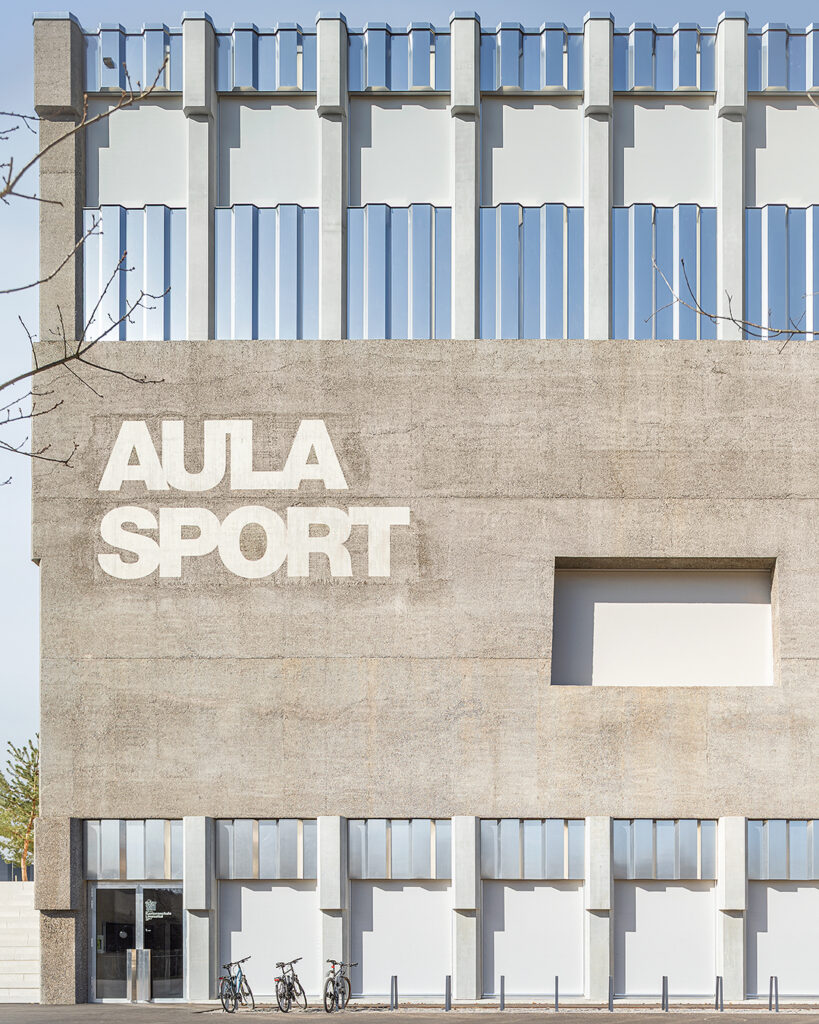 Architecture Photography of a modern brutalist-style school buildings, Kantonsschule Limmattal, featuring light gray-brown recyled-concrete facades and rectangular windows on the exterior, designed by PENZISBETTINI in Urdorf, Zürich.