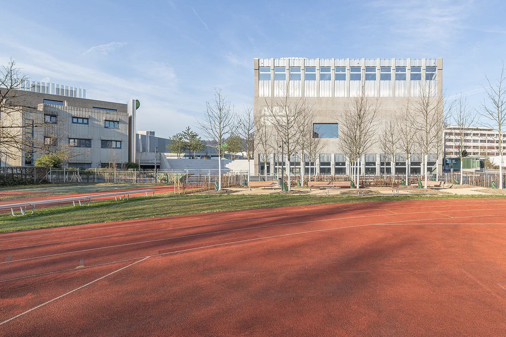 Architecture Photography of a modern brutalist-style school buildings, Kantonsschule Limmattal, featuring light gray-brown recyled-concrete facades and rectangular windows on the exterior, designed by PENZISBETTINI in Urdorf, Zürich.