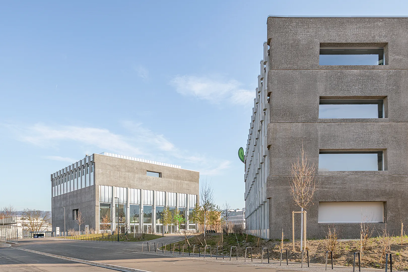 Architecture Photography of a modern brutalist-style school buildings, Kantonsschule Limmattal, featuring light gray-brown recyled-concrete facades and rectangular windows on the exterior, designed by PENZISBETTINI in Urdorf, Zürich.