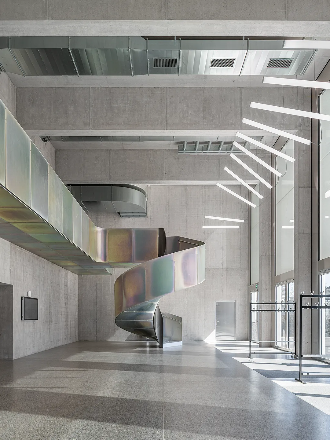 Architecture Photography of a modern brutalist-style school buildings, Kantonsschule Limmattal, featuring light gray-brown recyled-concrete facades, interior view of the entrance with prefabricated concrete structure by ingegneri pedrazzini guidotti, designed for PENZISBETTINI in Urdorf, Zürich.