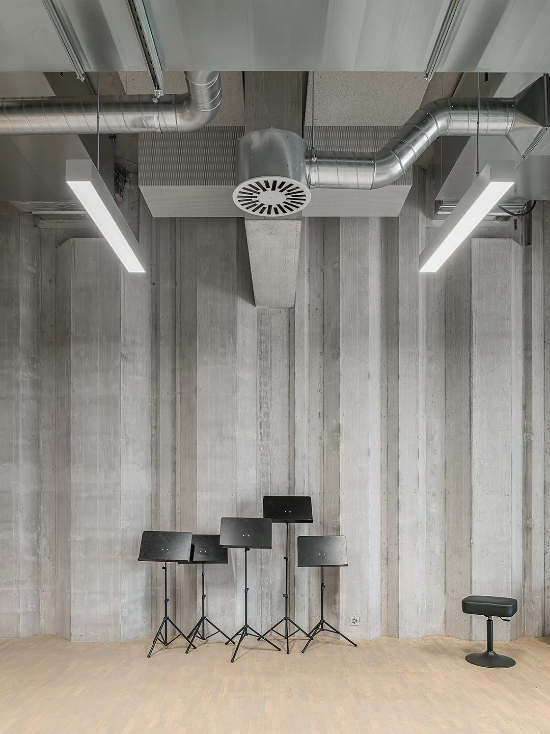 Architecture Photography of a modern brutalist-style school buildings, Kantonsschule Limmattal, featuring light gray-brown recyled-concrete facades, interior view of the music classroom with prefabricated concrete structure by ingegneri pedrazzini guidotti, designed for PENZISBETTINI in Urdorf, Zürich.